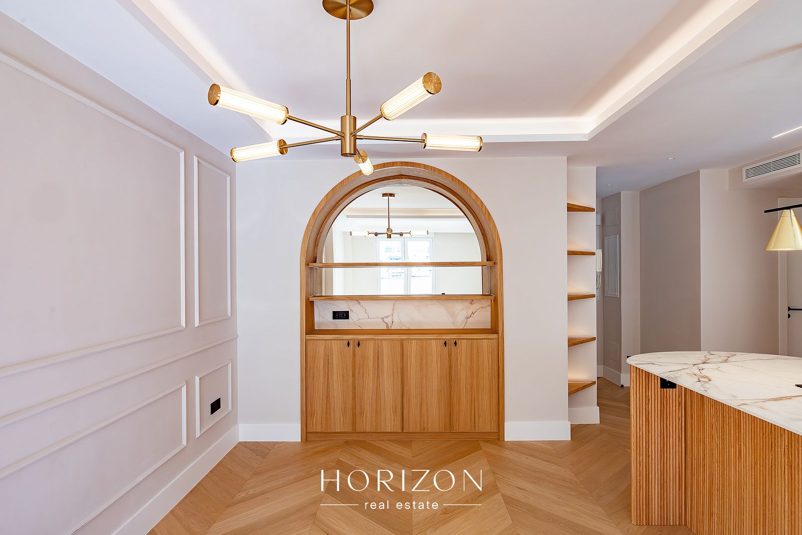 Dining area with arched oak niche and brass chandelier after renovation