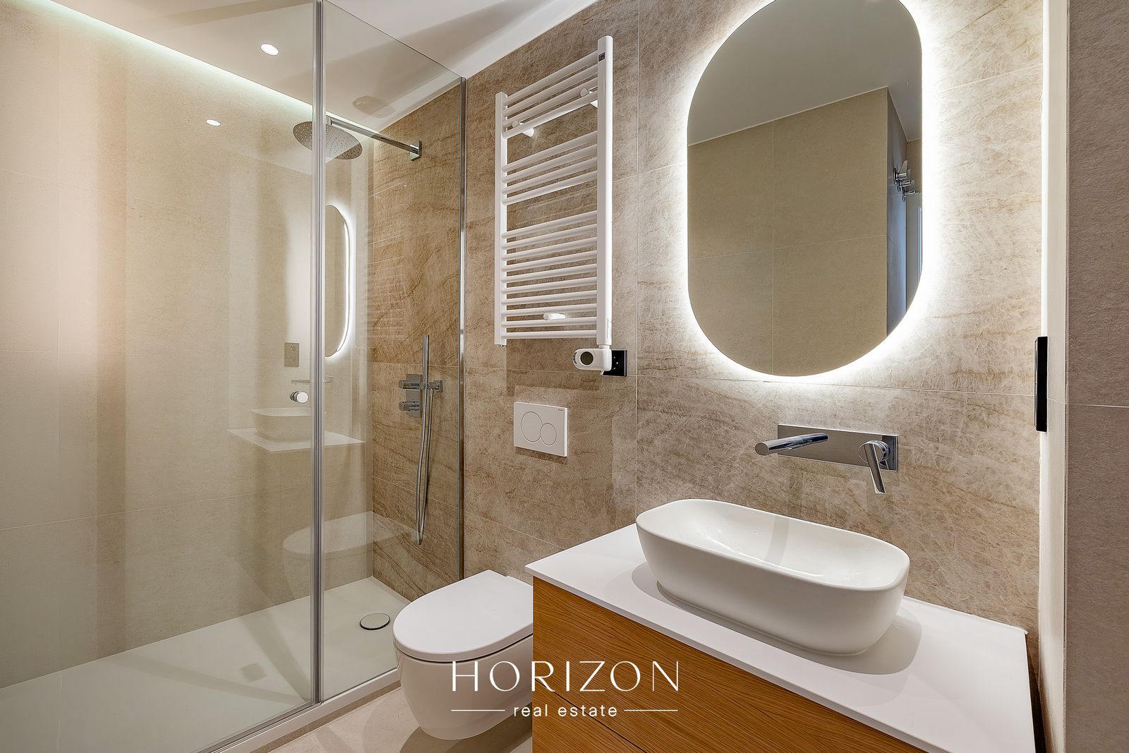 Bathroom with walk-in shower and backlit mirror after renovation