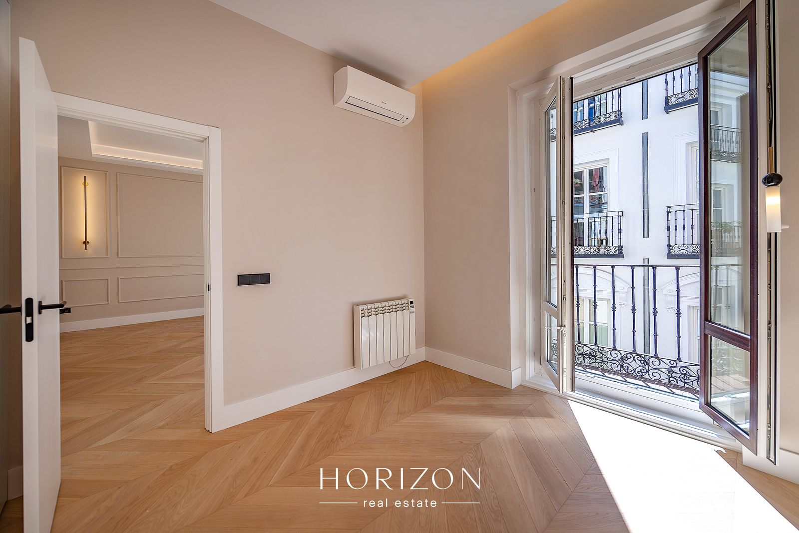 Bedroom with balcony doors open onto the street after renovation