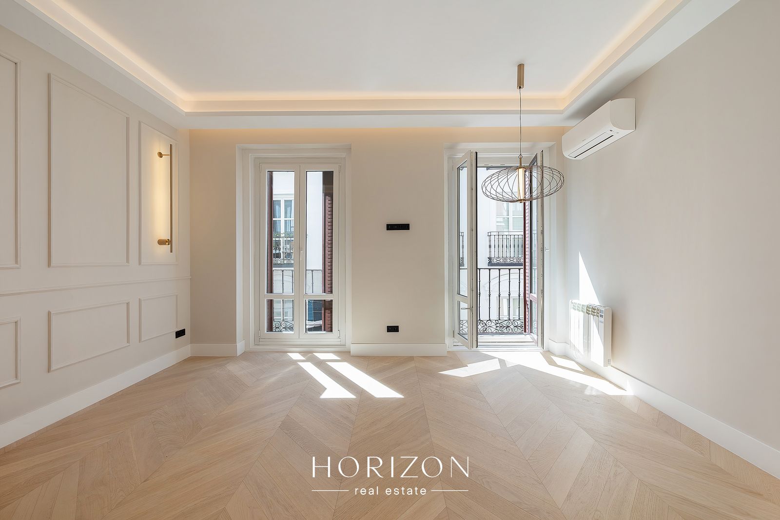 Living room after renovation, with wall panelling, brass sconces and balcony doors
