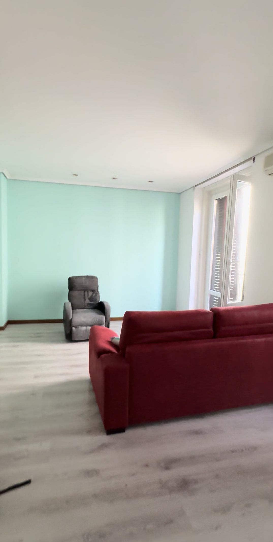 Living room before renovation, with aqua walls and laminate floor